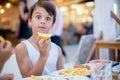 Sweet child, cute boy, eating fish and chips in a restaurant on the beach with lemon, focus on the lemon Royalty Free Stock Photo