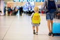 Sweet childre, brothers, boys, waking hand in hand at the airport, carrying suitcases and backpacks