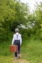 Sweet children in vintage clothing, hat, suspenders and white shirts, holding suitcase, running in the park Royalty Free Stock Photo