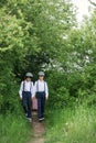 Sweet children in vintage clothing, hat, suspenders and white shirts, holding suitcase, running in the park Royalty Free Stock Photo