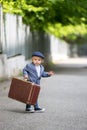 Sweet children in vintage clothing, hat, suspenders and white shirts, holding suitcase, running in the park Royalty Free Stock Photo