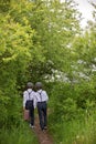 Sweet children in vintage clothing, hat, suspenders and white shirts, holding suitcase, running in the park Royalty Free Stock Photo