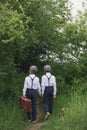 Sweet children in vintage clothing, holding suitcase, running in the park Royalty Free Stock Photo