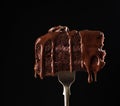 Sweet chocolate cake on fork on black macro background