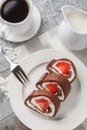 Sweet chocolate cake roll filled with strawberries and cream cheese served with coffee close-up. Vertical top view Royalty Free Stock Photo