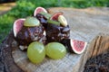 Mini Chocolate Cakes with Fig, Kiwi, Banana, and Grape Toppings on a Rustic Wooden Log Royalty Free Stock Photo
