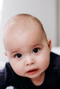 Sweet chubby cheeky baby boy lying on his tummy on the bed. Funny face expression