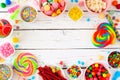 Sweet and colorful candy buffet frame, above view table scene over a white wood background