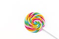 Sweet colorful spiral shaped lollipop lying in lower right corner, isolated on white background, top view. Royalty Free Stock Photo