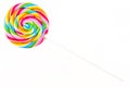 Sweet colorful spiral shaped lollipop lying in upper left corner, isolated on white background, top view. Royalty Free Stock Photo