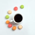 Sweet and colourful macaroons with cup of coffee on white background. Traditional french dessert. Top view, flat lay Royalty Free Stock Photo