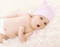 Sweet comfortable baby in hat yawns lying on the bed Royalty Free Stock Photo