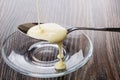 Sweet condensed milk in spoon above transparent saucer