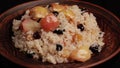 Sweet cooked rice with apples, sultanas and dried fruits in ceramic plate close-up. Oriental cuisine, sweet pilaf. Video looped