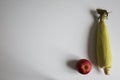 Sweet corn cob and red apple flat lay on white table. Homegrown real organic vegetable and fruit. Selective short focus