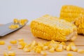 Sweet corn kernels are cut from the cob on a wooden cutting board with a knife. Using corn kernels in cooking to make delicious Royalty Free Stock Photo