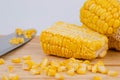 Sweet corn kernels are cut from the cob on a wooden cutting board with a knife. Using corn kernels in cooking to make delicious Royalty Free Stock Photo