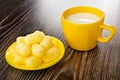 Sweet corn sticks in yellow glass saucer, cup with milk on wooden table Royalty Free Stock Photo