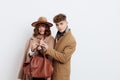 a sweet couple in love, a man and a woman in stylish autumn clothes stand on a white background and a guy helps hold