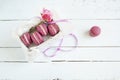 Sweet crimson french macaroons and rose with box on light dyed wooden background