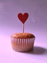 Sweet cupcake with a heart on a stick on a pink background Royalty Free Stock Photo