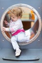 Sweet curly baby girl sliding on a playground