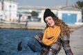 Sweet curly teen sitting on the edge of the port