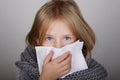 Cute blond hair little girl blowing her nose with paper tissue. Child winter flu allergy health care concept