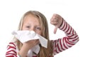 Sweet and cute blond hair little girl blowing her nose with paper tissue having a cold feeling sick Royalty Free Stock Photo