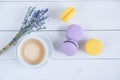 Sweet delicious violet and yellow macarons and cup of latte or americano and branch of fragrant lavender on white wooden