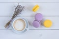 Sweet delicious violet and yellow macarons and cup of latte or americano and branch of fragrant lavender on white wooden