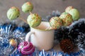 Sweet dessert: cake pops in icing with bright sprinkles on sticks in a white mug on a gray background. Close-up