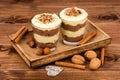 Sweet dessert - chocolate and vanilla pudding in glasses served on the wooden tray with nuts and cinnamon sticks. Royalty Free Stock Photo