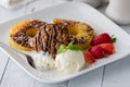 A sweet dessert of fried pineapple with ice cream and a chocolate lace cookie.