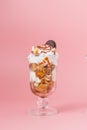 Sweet dessert in glass with biscuit and whipped cream on pink bsckground, selective focus and blank space