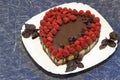 Sweet dessert for lovers. Vegan chocolate raw foods cake topped with raspberries on white plate with basil leaves on Royalty Free Stock Photo