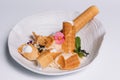 Sweet dessert. Wafer tubules with a delicate protein cream and a small sieve with powdered sugar on a white round tray