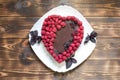 Sweet dietary present for lovers on wooden background. Vegan chocolate cheesecake with raspberries on white plate with