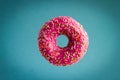 donut with pink berry chocolate icing and sprinkles flying on blue background