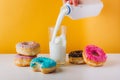 Sweet donuts with man hand pouring milk