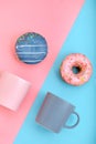 Sweet donuts pink and blue with a mug of coffee. Blue and pink background, game of colors, color conflict. Mock up for