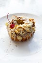 A plate with two tasty glazed donuts with chocolate, nuts and red cherry