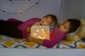 Sweet dreams, good night and night lamps promo concept. Close up of two beautiful 10 year old girls sisters, lying