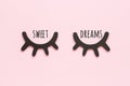 Sweet dreams text and decorative black wooden eyelashes, closed eyes on pink background. Concept Good night. Top view Copy space Royalty Free Stock Photo