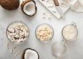 Sweet dried coconut flakes with bites and slices in glass jar with ripe coconuts on light table.Top view Royalty Free Stock Photo