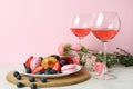 Sweet food, wine and flowers against pink background Royalty Free Stock Photo