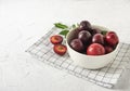 Sweet fresh delicious red plums on white bowl and towel white wood table summer fruits