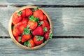 Sweet fresh juicy organic ripe strawberries in wooden bowl on wooden surface on bright sunny day outdoors Royalty Free Stock Photo