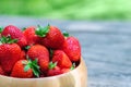 Sweet fresh juicy organic ripe strawberries in wooden bowl on wooden surface outdoors in garden or backyard Royalty Free Stock Photo