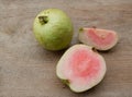 pink guava ,red guava (psidium guajava) fruit with green leaf and half slices,whole isolated on a wooden table backdrop